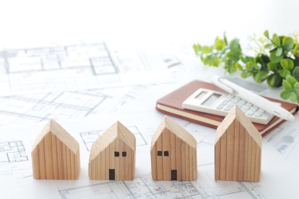 Vier schematische Holzhäuser auf Bauplan